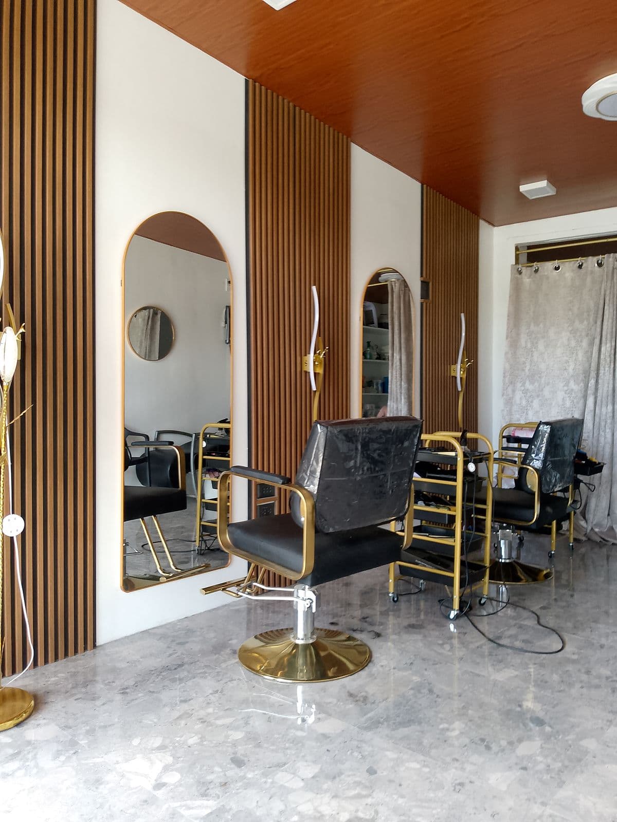 Gold-framed styling chairs along marble flooring